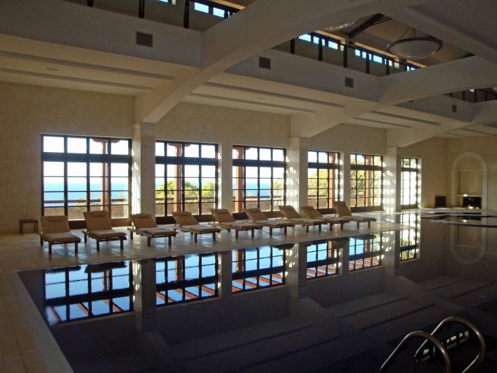 View of the glass wall of the swimming pool with French window opening system and fixed transom window